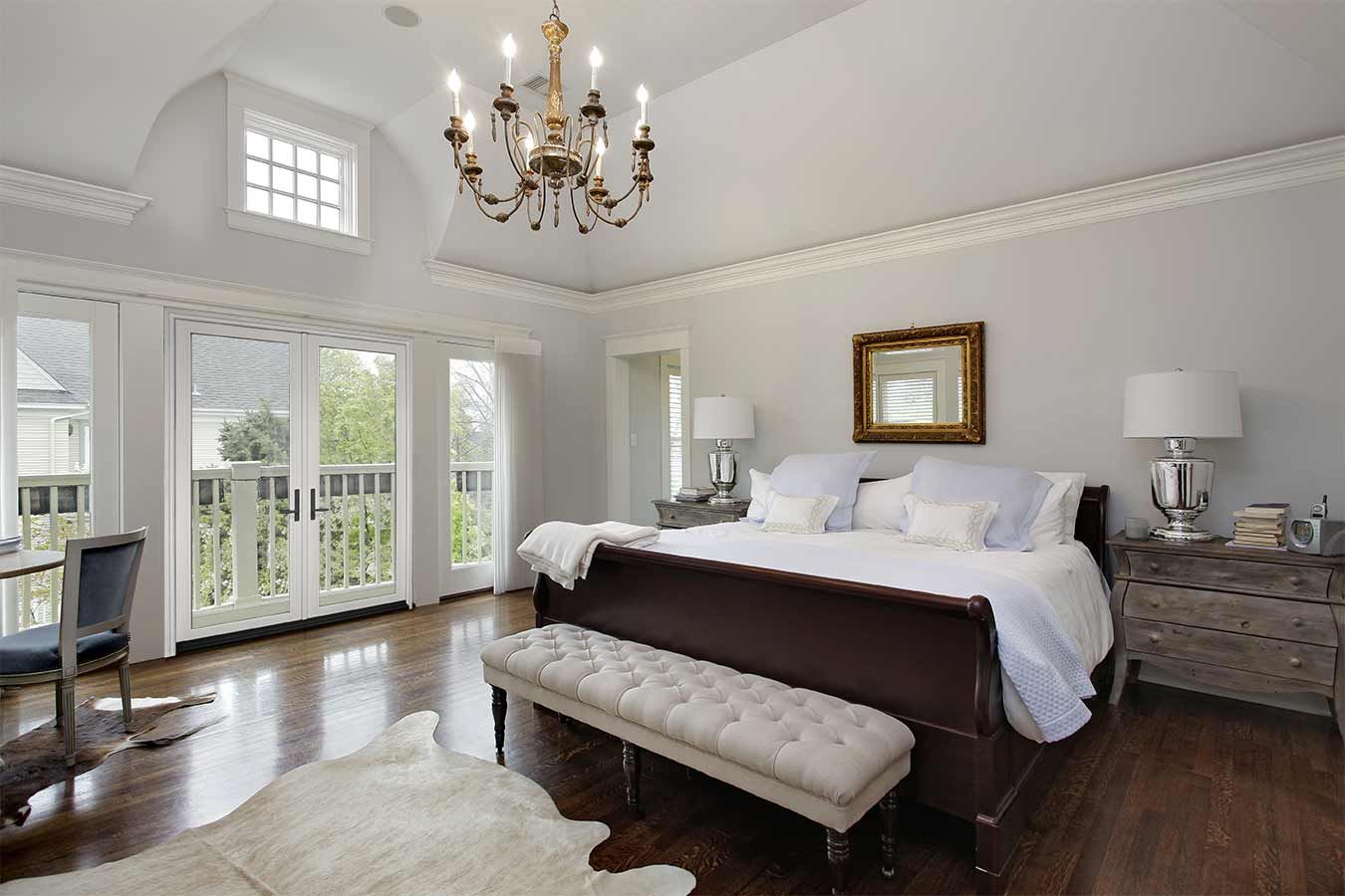 Bedroom with tall white French doors and an upper gridded window